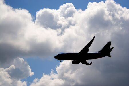 A silhouette of a commercial passenger plane over a blue sky in its descent to land.の写真素材