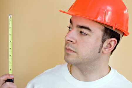 A young construction worker using a tape measure. Plenty of copyspace.の写真素材