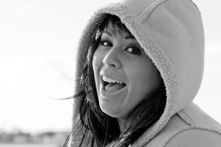 A young hispanic woman with a hood on her head in black and white.