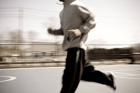 Abstract blur of a young man warming up by jogging at the basketball court.  Intentional motion blur.の写真素材