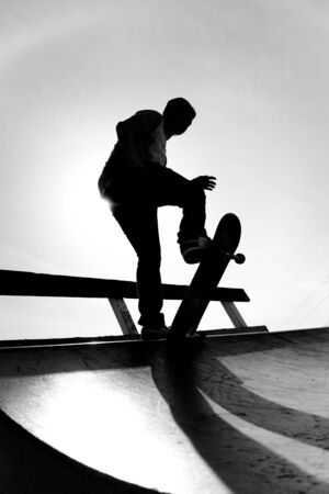 Silhouette of a young skateboarder at the top of the ramp.の写真素材
