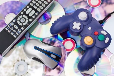 Remote control wireless computer mouse and video game controller over a bed of dvd disks isolated over white.の写真素材