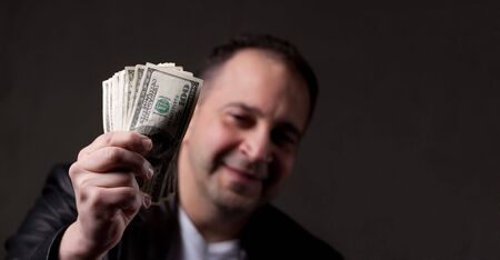 A happy middle aged man holding a handful of money with copyspace.の写真素材
