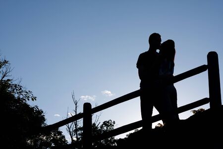 Silhouette of an affectionate couple romantically kissing each other in the early evening hours.の写真素材