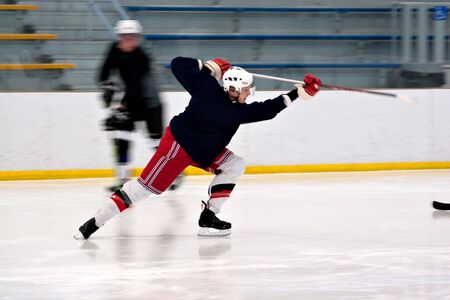 A hockey player shooting the puck as he speeds down the ice.  Slight motion blur.の写真素材