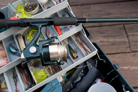 A fishermans rod reel and tackle box filled with lures and bait ready for the start of fishing season.の写真素材
