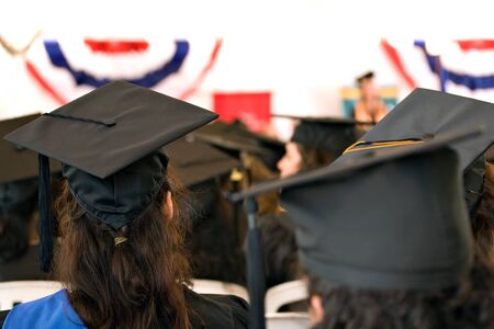A group of college or high school graduates wearing the traditional cap and gown.  Shallow depth of field.の写真素材
