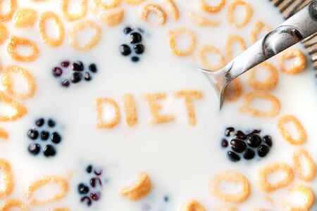 The word DIET spelled out of letter shaped cereal pieces floating in a milk filled cereal bowl.の写真素材