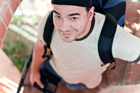 A young photographer in his late twenties with his camera backpack and dslr in hand walking down a spiral staircase. Shallow depth of field.の写真素材