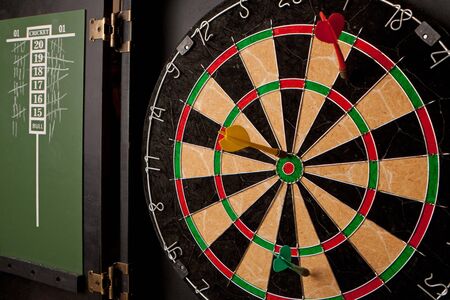 A professional dart board enclosed in a cabinet with slate chalkboard score boards.