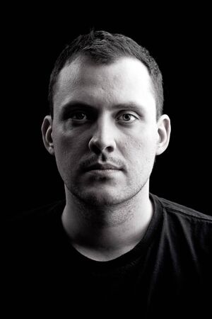 Low key portrait of a serious man in his late twenties in black and white.  Shallow depth of field.の写真素材