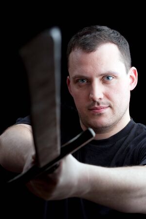 A young man wields a medieval style sword over a black background.