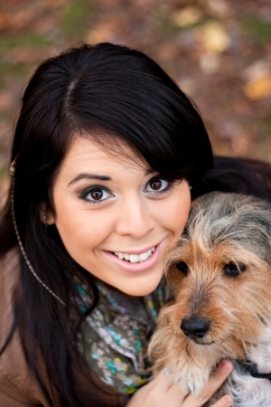 A young woman in her 20s by the sea shore holds a cute mixed breed beagle yorkshire terrier dog also called a Borkie.の写真素材