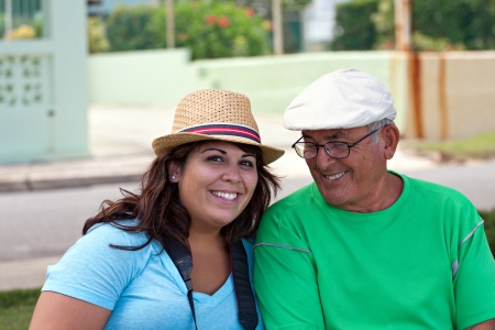 A older Hispanic senior citizen man sits outdoors in a tropical setting with his granddaughter.の写真素材