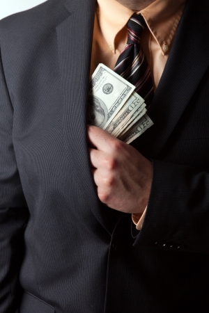 Close up of a business mans hand hiding money in his suit jacket pocket.の写真素材