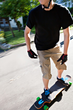 Action shot of a longboarder skating on an urban road. Slight motion blur.の写真素材
