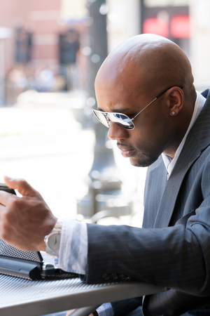 A business man in his early 30s working on his laptop or netbook computer outdoors.の写真素材