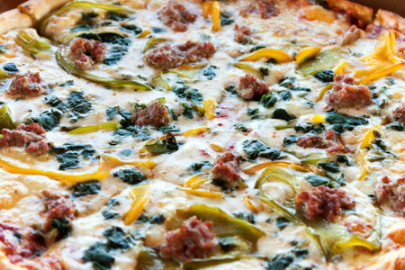 Close up detail of a fresh specialty pizza with spinach peppers and sausage.  Shallow depth of field.の写真素材