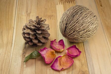dried rose petals on wood ground with cone pine.の写真素材