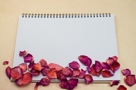 Black notepad. Realistic template notebook. Blank cover design. with dried rose petals and leaf. on cardboard background.の写真素材