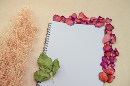 Black notepad. Realistic template notebook. Blank cover design. with dried rose petals and leaf. on cardboard background.の写真素材