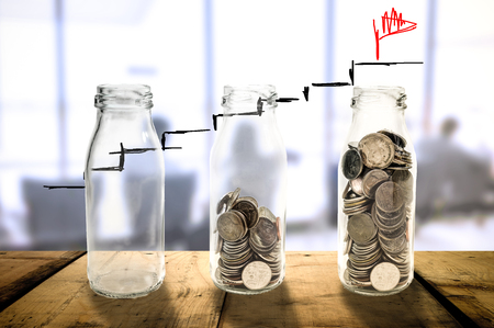 Business investment growth Beautiful concept collecting coins in glass bottle on wood planks floor, Saving money concept.の写真素材