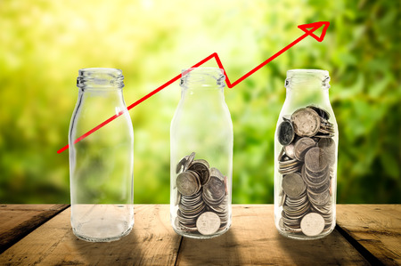 Business investment growth Beautiful concept collecting coins in glass bottle on wood planks floor, Saving money concept.の写真素材