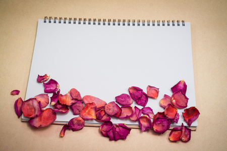 Black notepad. Realistic template notebook. Blank cover design. with dried rose petals and leaf. on cardboard background.の写真素材