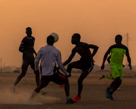 Boys and children playing football at sunset on a dusty pitch in Maroua, the capital city of the Far North Region of Cameroonのeditorial素材