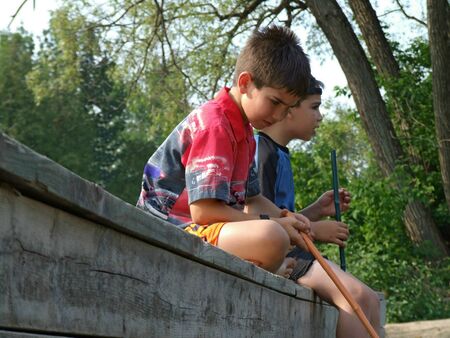 Two boys sitting on a dock with fish nets.の写真素材