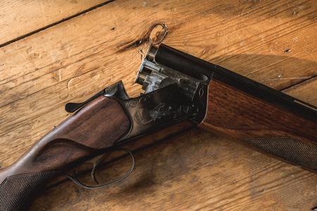 Shotgun on a wooden floor charger with bullets and some spare bulletsの写真素材