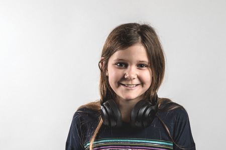 Teenage girl with headphone around her neck and on white background, smiling, party time, chilling timeの写真素材