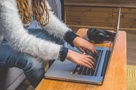 Teenage girl in the Conservatory with nordic sofa, laptop and headphone, wooden floor, yellow rugの写真素材