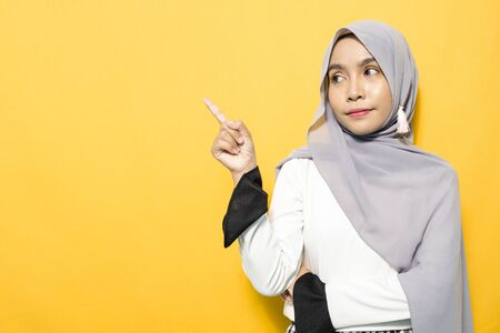 Portrait of young woman wearing white shirt and pointing empty spaceの写真素材