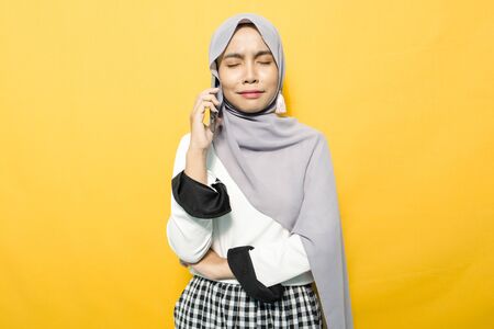Portrait of young Asian woman talking on smartphone in white shirtの写真素材
