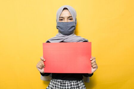 Portrait of Asian woman wearing mask and holding red paper