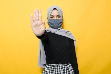 Asian woman wearing mask and making stop sign