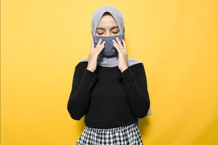 Asian woman wearing mask and holding mouthの写真素材