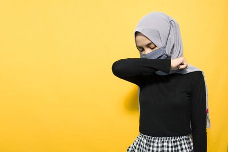 Asian woman wearing mask and covering mouth with elbowsの写真素材