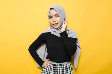 Asian woman smiling wearing hijab on yellow backgroundの写真素材