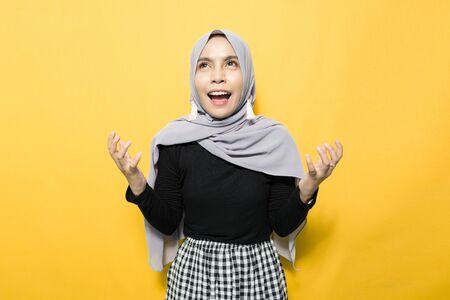 Portrait of Asian woman wearing hijab on yellow backgroundの写真素材
