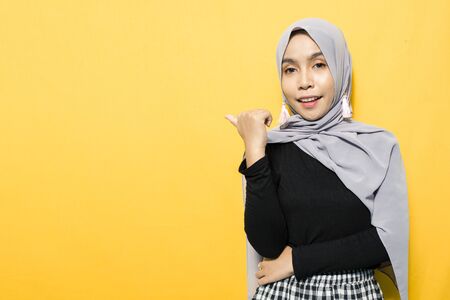 Asian woman wearing hijab points to empty spaceの写真素材