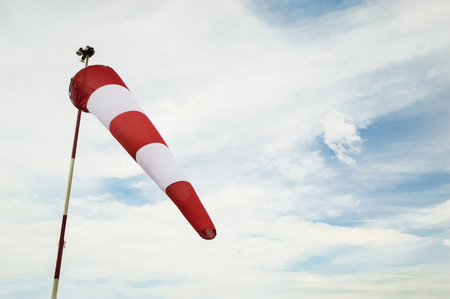 Windsock waving on clouded blue sky background