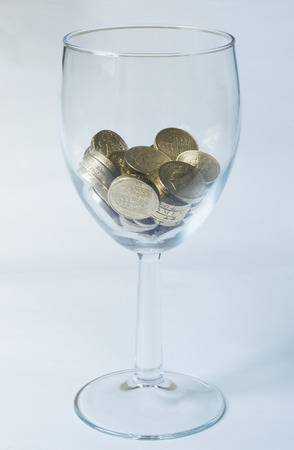A glass containing British pound coins under blue lightの写真素材