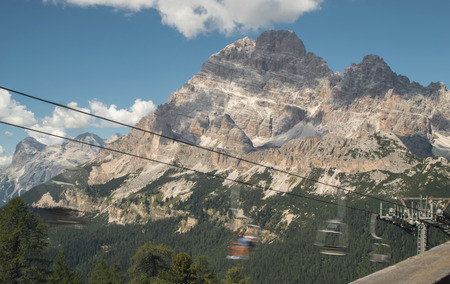Landscape of huge Dolomites in the Italian Alps near Misurina with green forest below and moving cable railway in sunny dayの写真素材