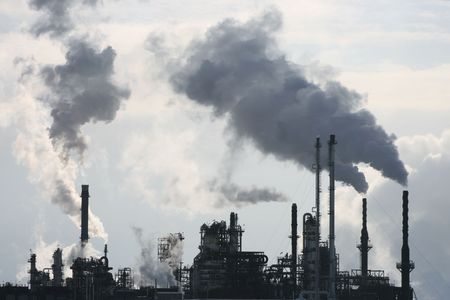 Long shot of a refinery releasing smog into the winter air