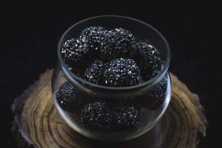 Fresh and delicious tilgul sweet laddu in a glass bowl. Sesame laddu for Indian festival, Special treat prepeared on the ocassion of Makar Sankranti in India. Selective focusの写真素材