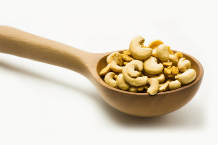 A white background with an individual cashew nut in a wooden spoon. looking up. Lay flatの素材