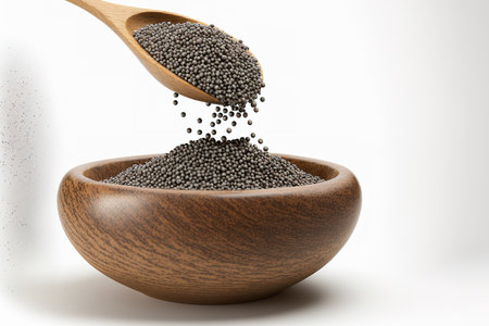 Chia seeds are dropping in a stream and filling a small wooden bowl in this side view, which is isolated on a white backgroundの素材