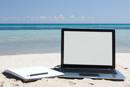 A notebook with a blank screen is seen on the ocean in the summer. The sea is gleamingの素材